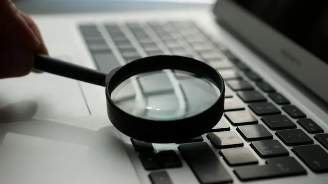A magnifying glass held over a laptop keyboard