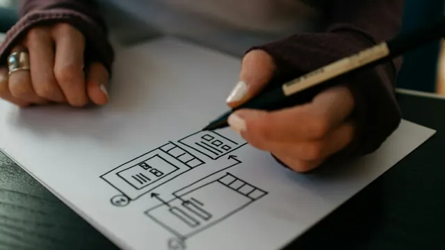 A person sketching a screen layout on paper